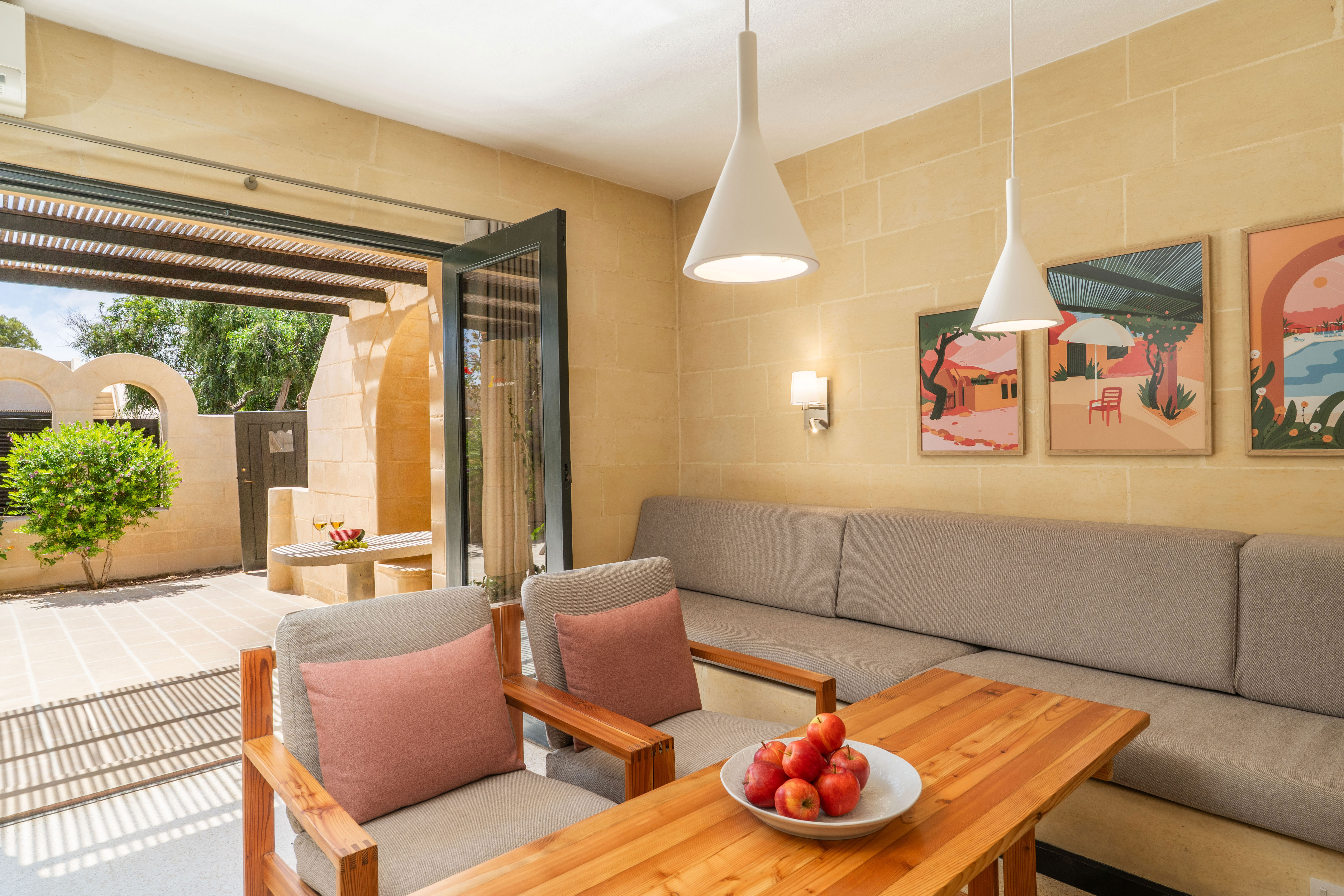 Stue i lejlighed på Mellieha: Sofa langs den ene væk, sofa bord og to lænestole. Udgang til terrasse.