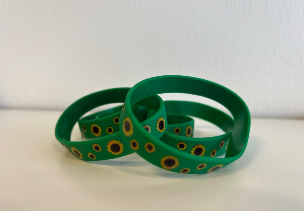 4-5 solsikkearmbånd i silikone liggende på plan flade