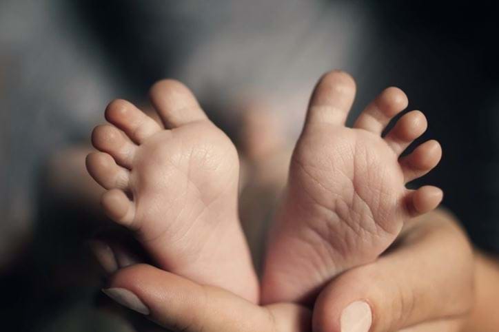 Foto af en hånd, der holder en babys små fødder
