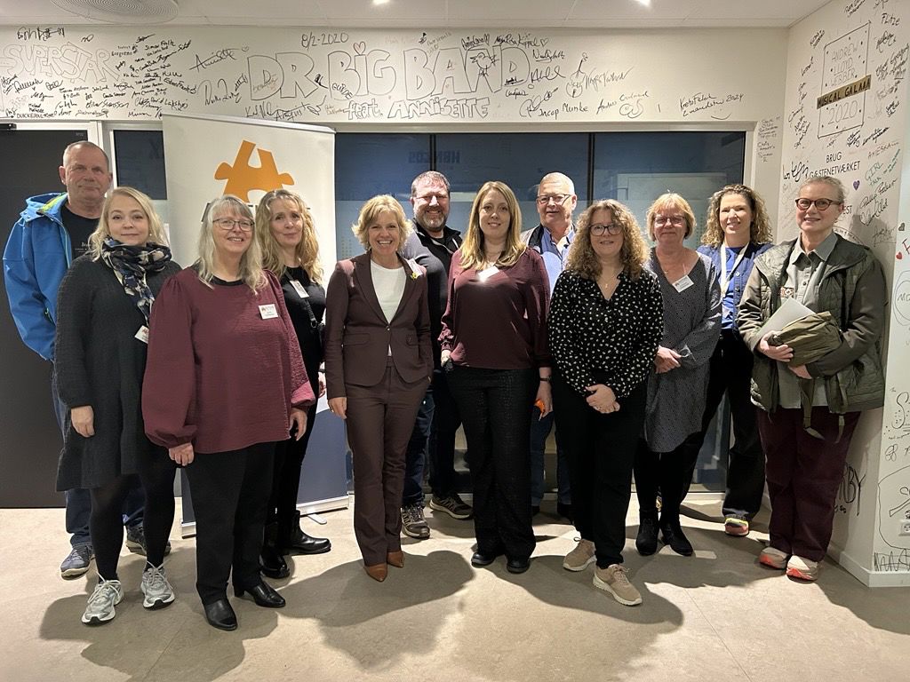 Gruppebillede af Autismeforeningens Hovedbestyrelse. 12 mennesker stående på række med Autismeforeningens logo på en rollup i baggrunden.