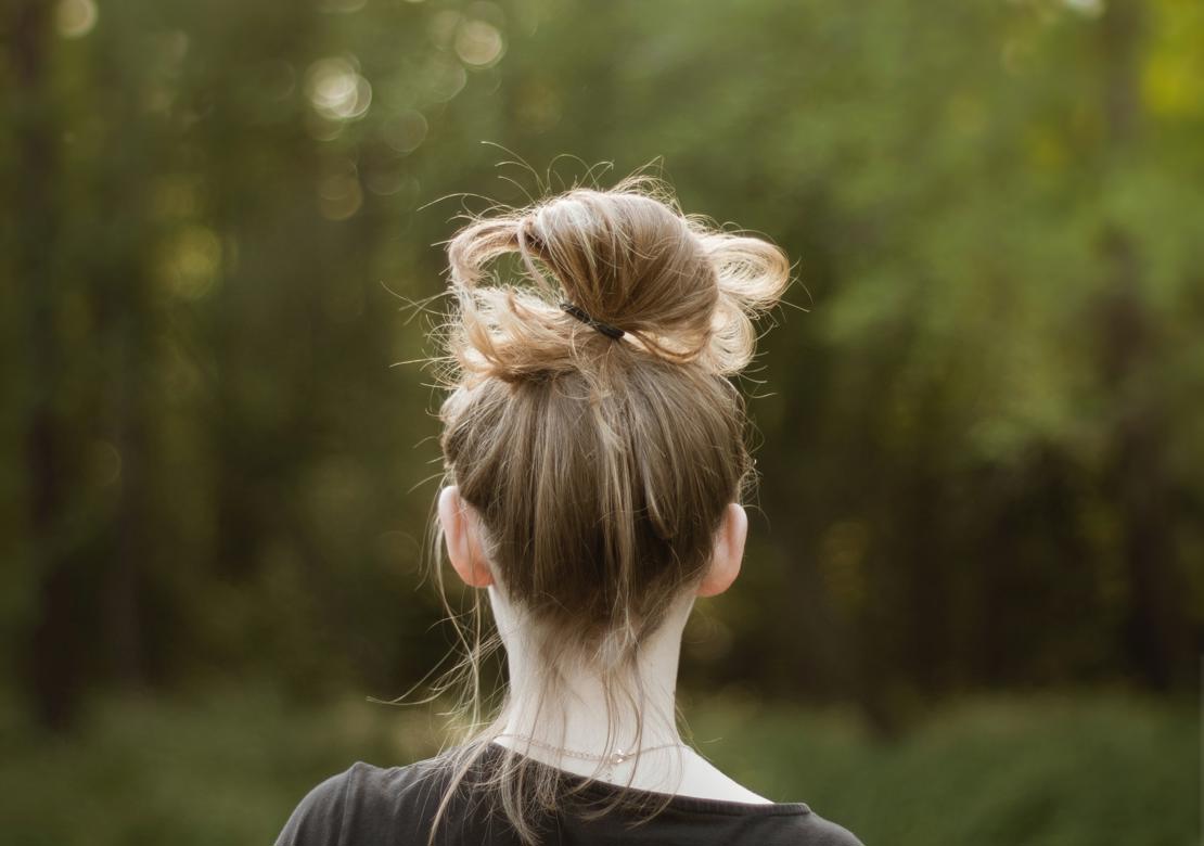 Pige set bagfra med træer billedets baggrund