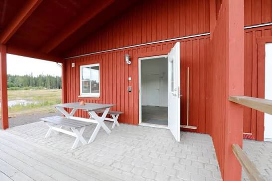 Overdækket og skærmet terrasse med underlag af fliser - i forbindelse med rød hytte