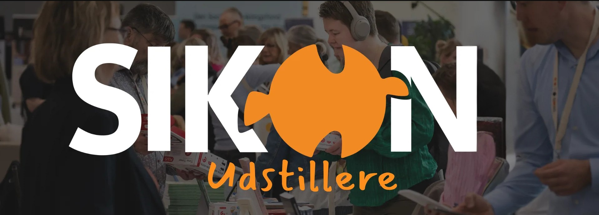 i baggrunden: oplægsholder taler foran publikum. i forgrunden teksten: SIKON Udstillere