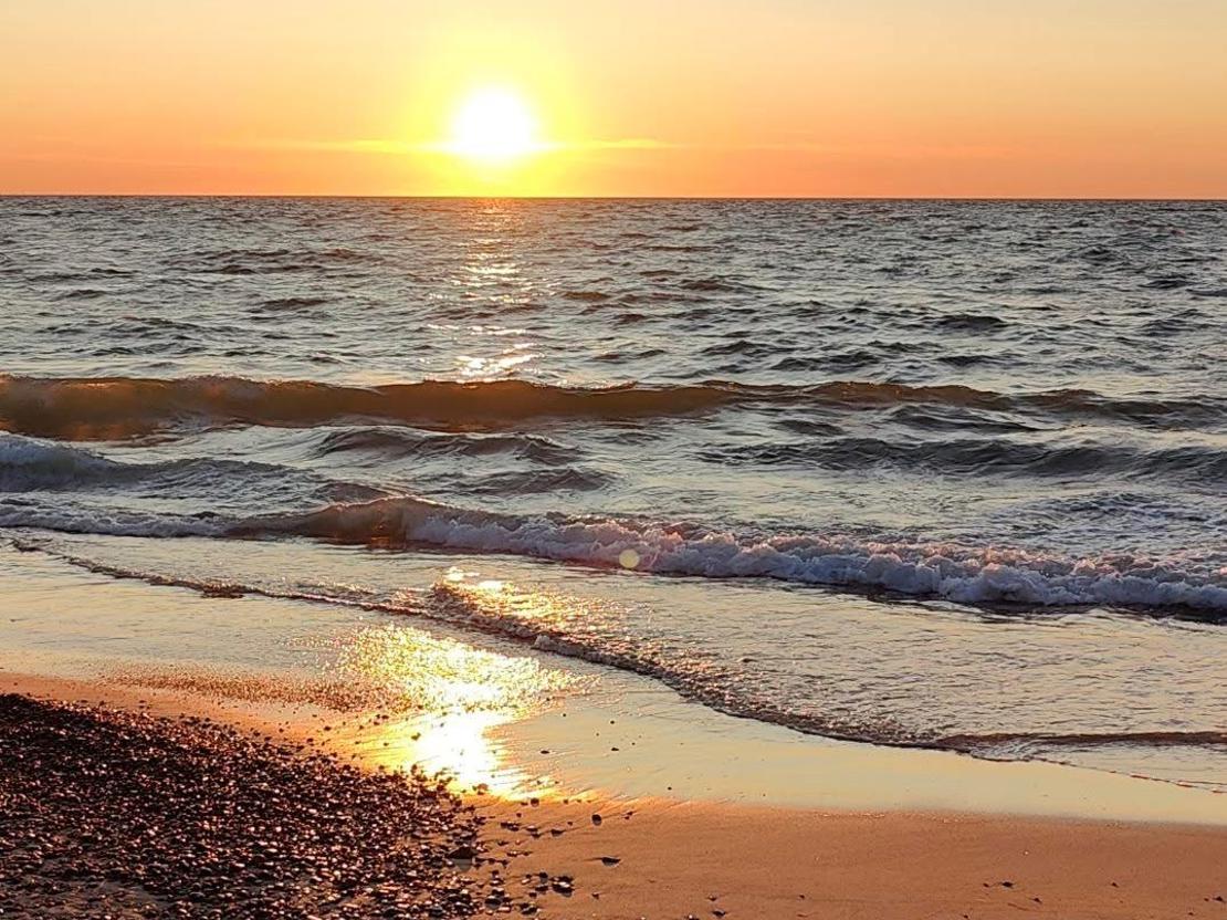 Aftensol genspejles i små bølger på stranden i Vigsø