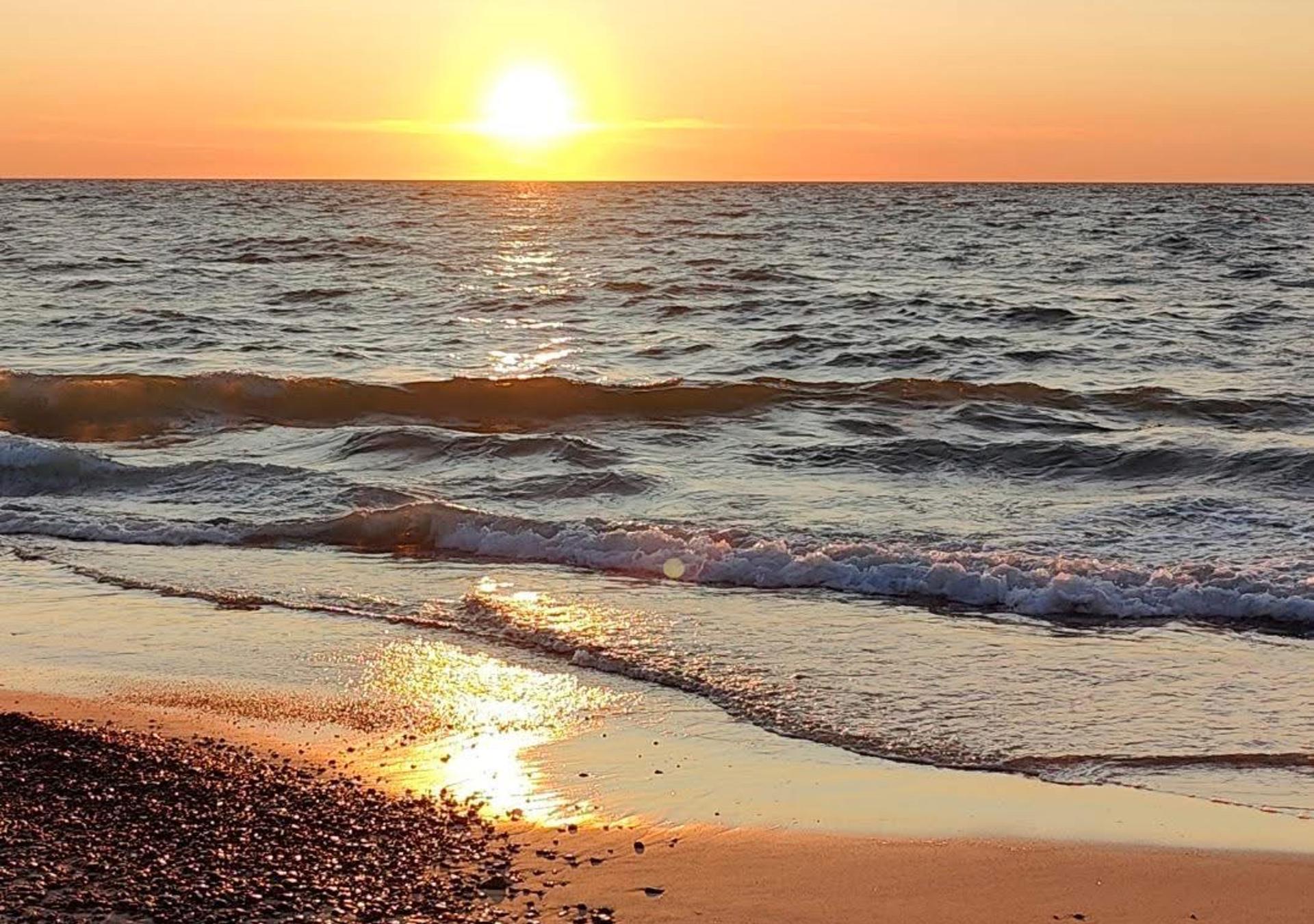 Aftensol genspejles i små bølger på stranden i Vigsø
