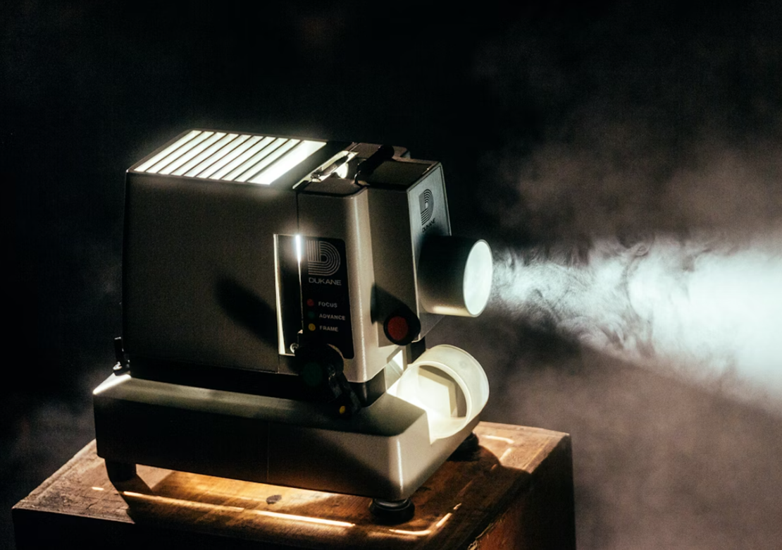 En filmfremviser lyser i et mørkt lokale