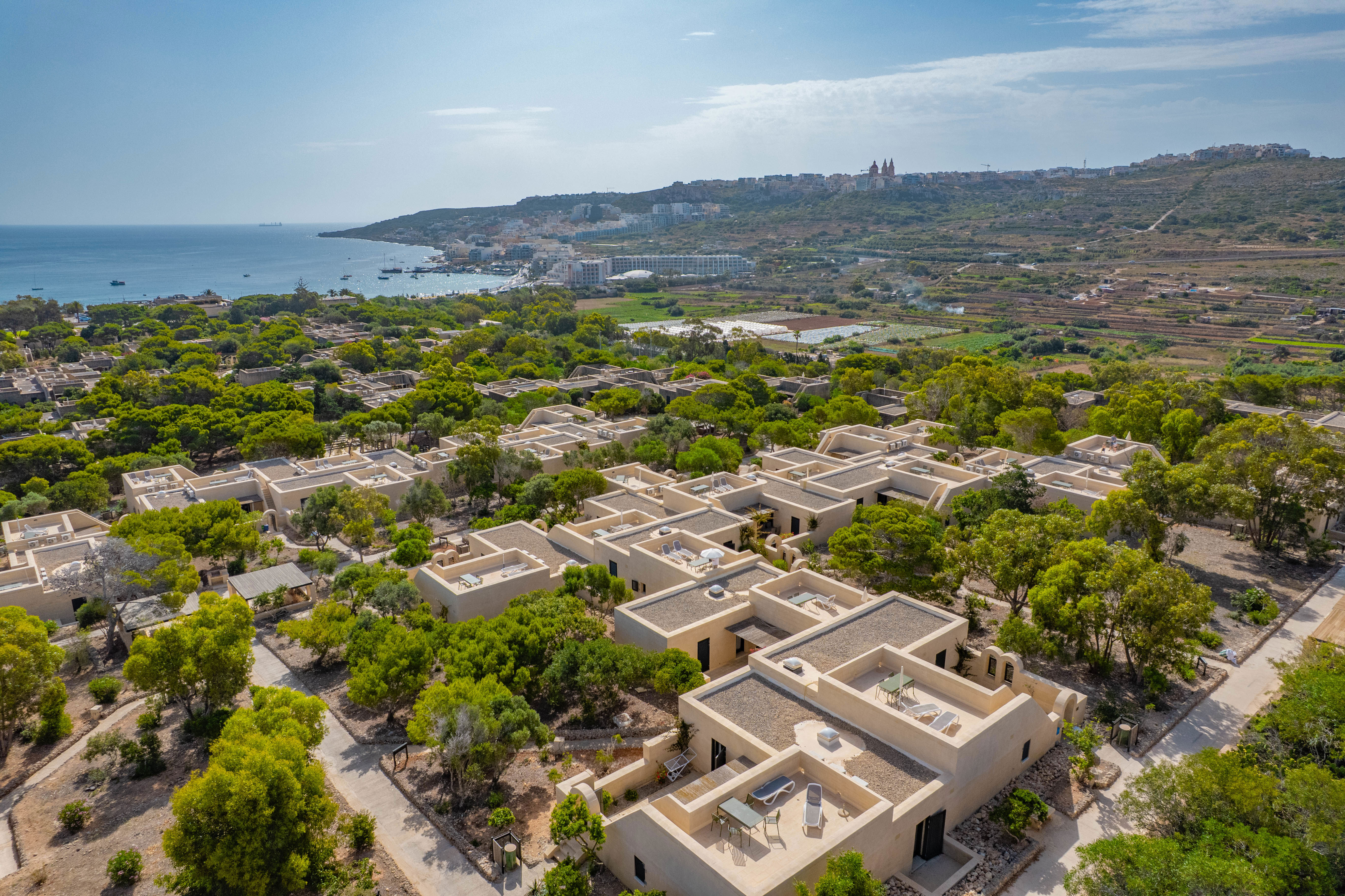 Mellieha Holiday Centre set fra luften. Lave bygninger med grønne planter