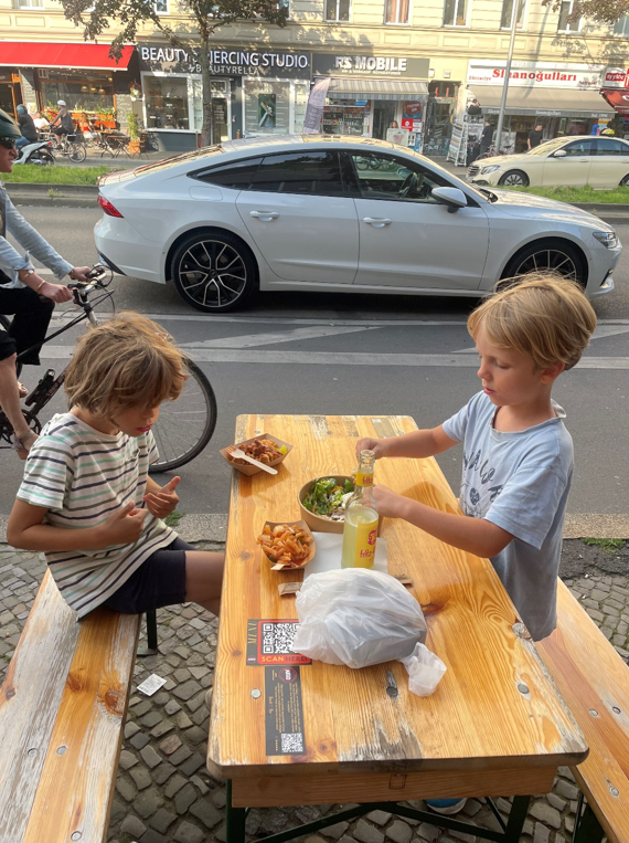 To drenge spiser mad ved bordebænkesæt i berlin