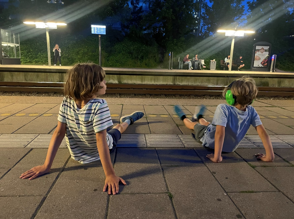 To drenge sidder på togperron om aftenen og venter på nattog 