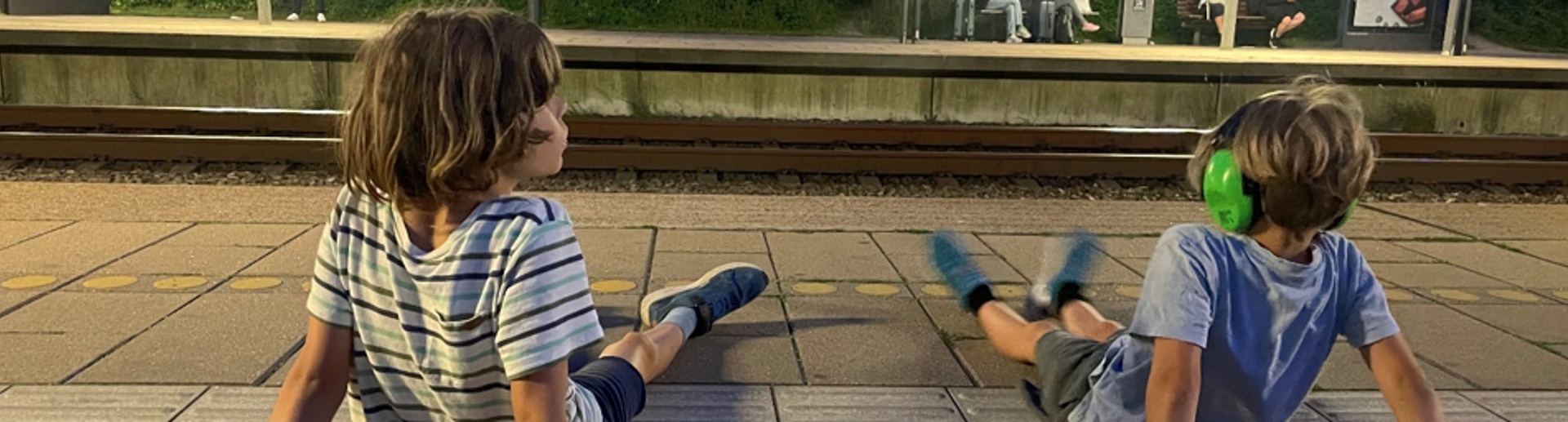 To drenge sidder på togperron om aftenen og venter på nattog