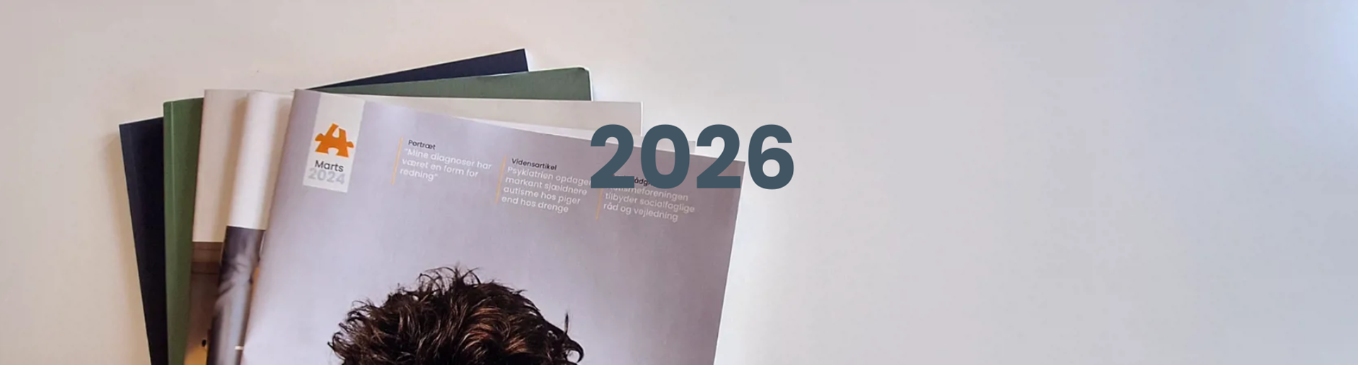 Toppen af en stak Autismebladet og årstallet 2026