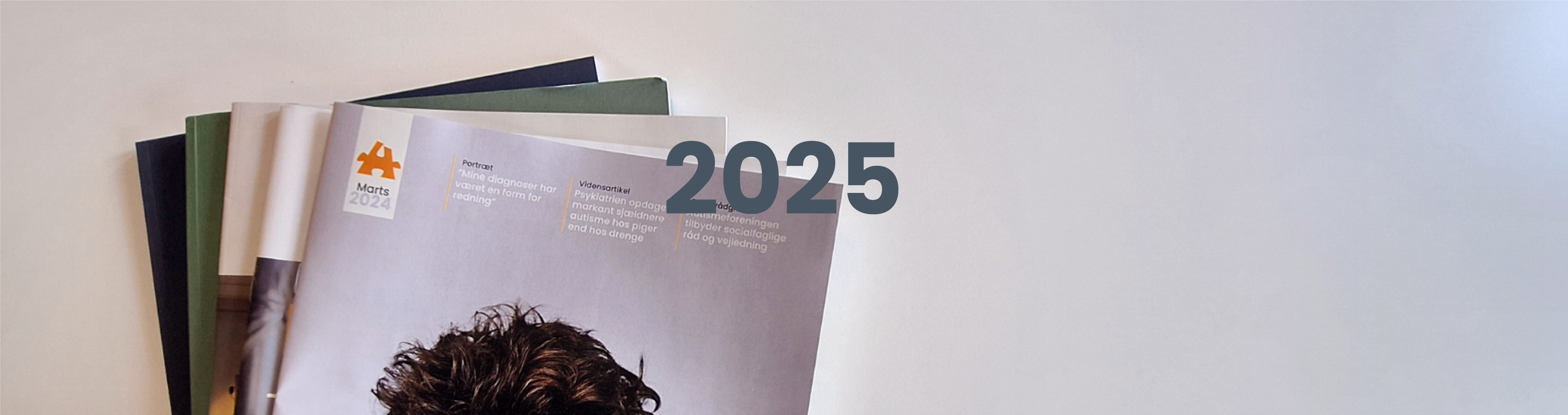 Toppen af en stak Autismebladet og årstallet 2025