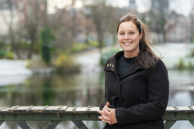Emilie Gade står smilende på en lille bro