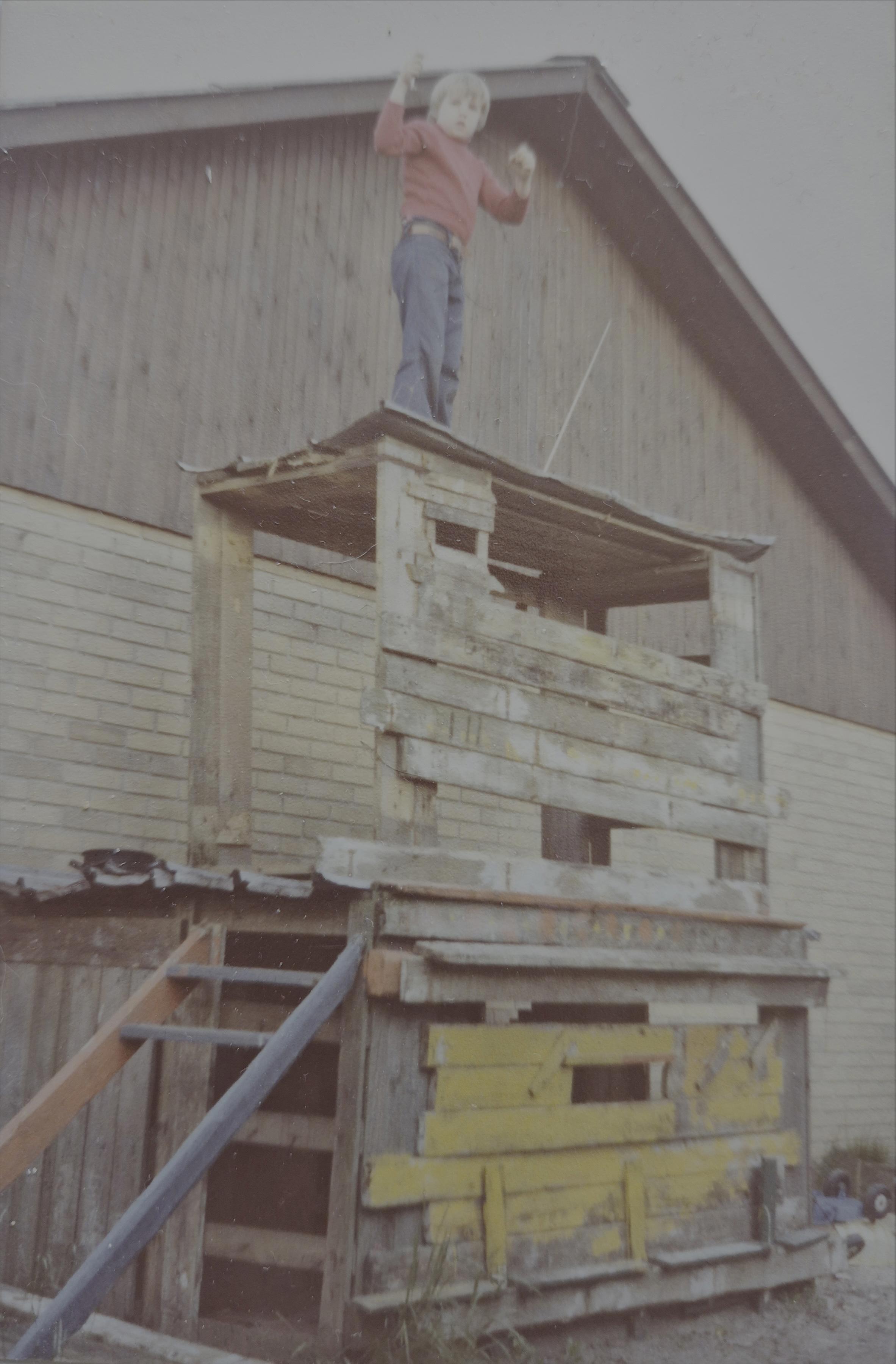 Torben som barn på toppen af konstruktionen af et toetagers legehus i træ