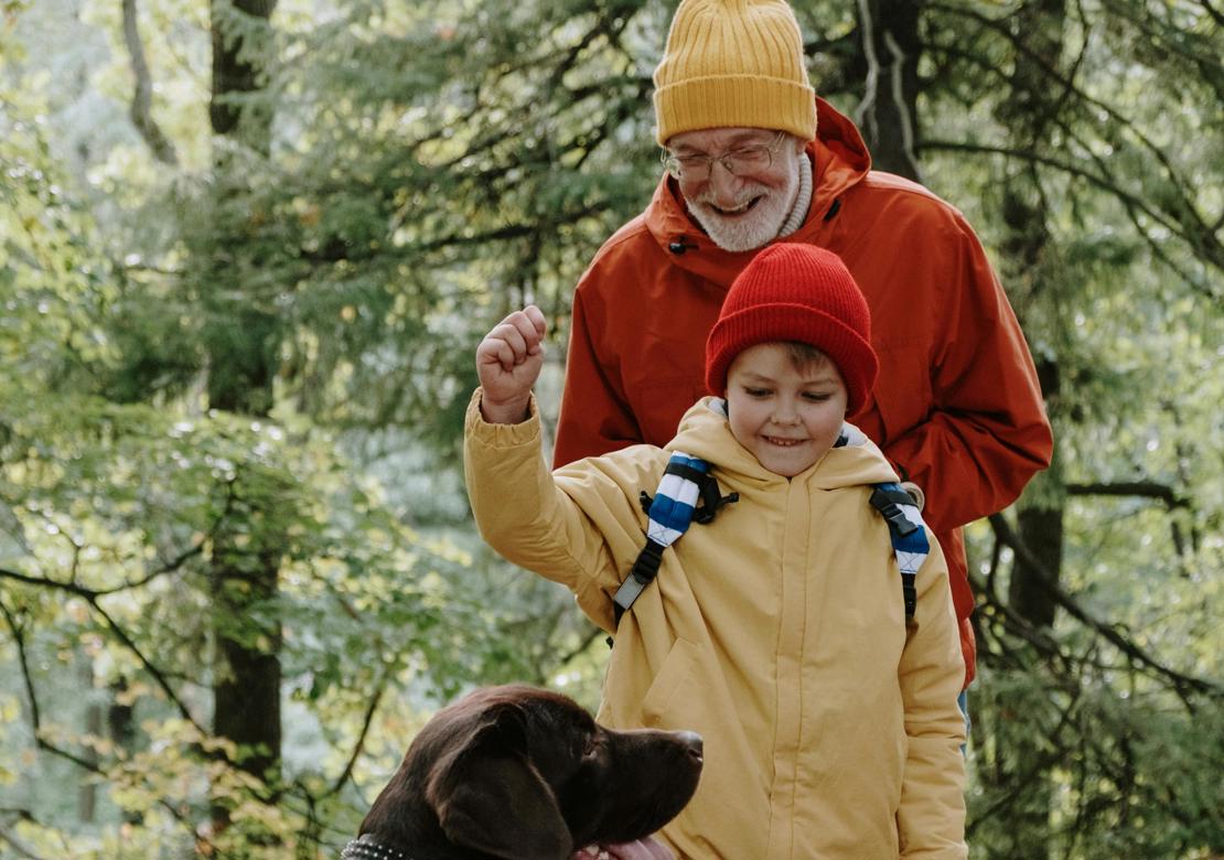 Ældre mand med ung dreng og hund i skoven