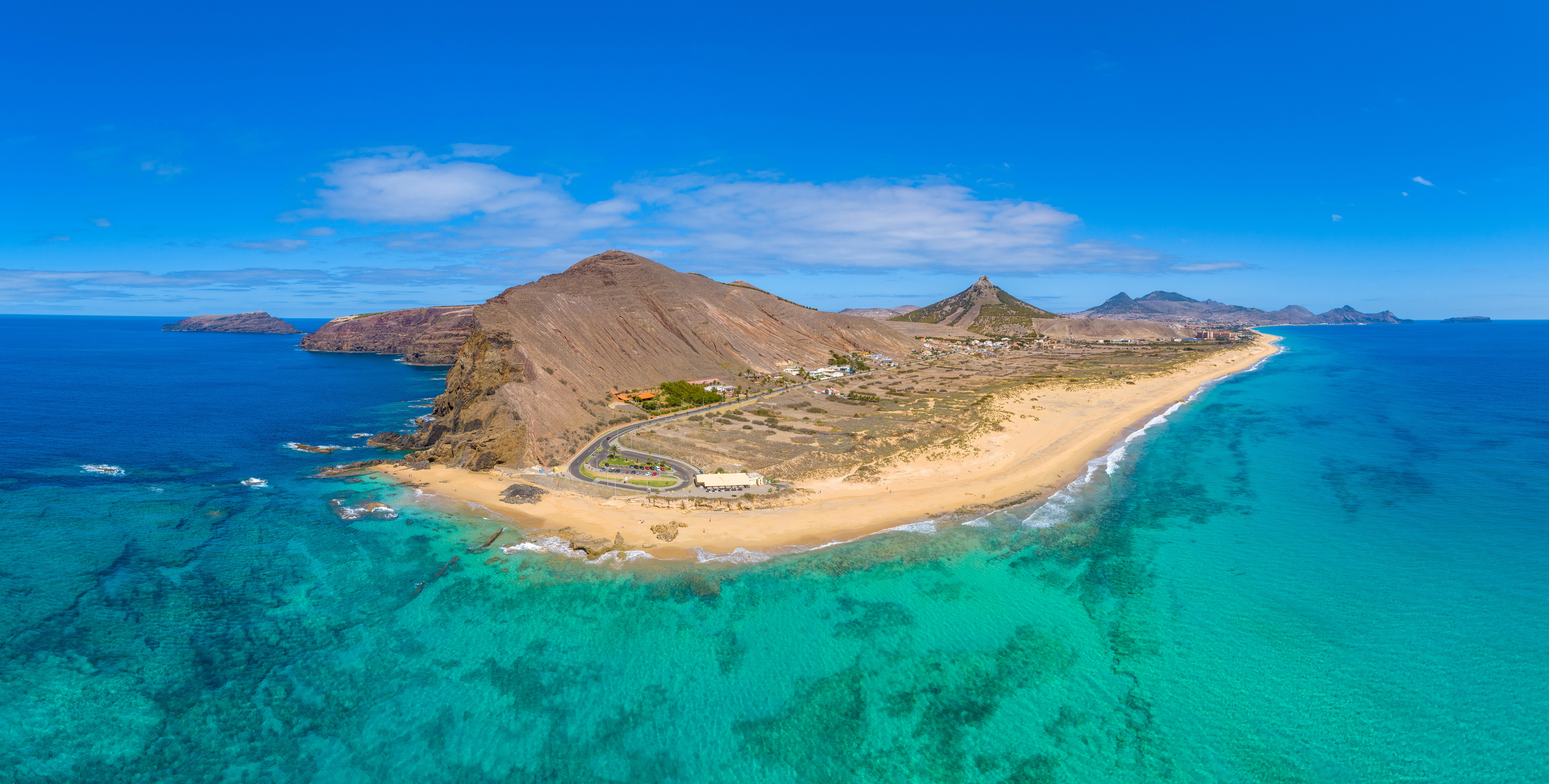 Flad ø med bjerg på den ene side midt i meget blåt vand