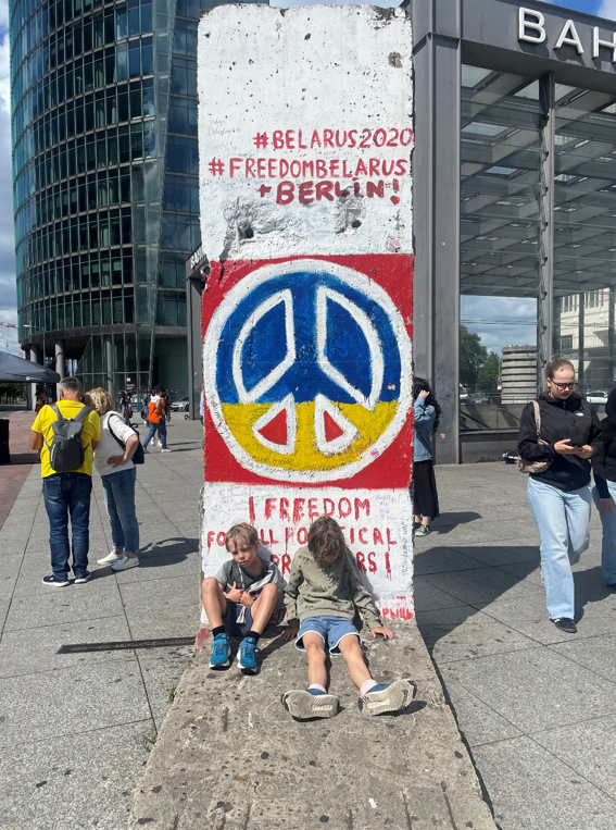 To trætte og våde drenge hviler ud ved resterne af Berlinmuren på Potzdamer Platz.