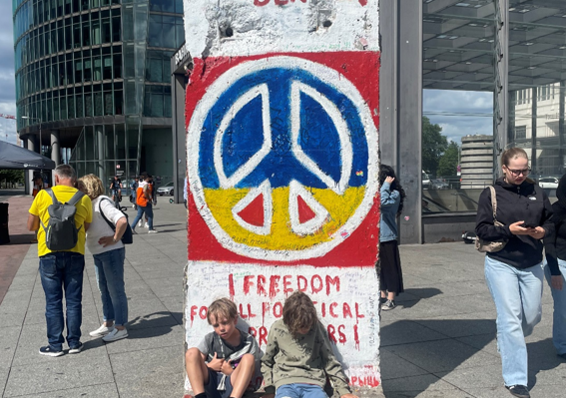 To trætte og våde drenge hviler ud ved resterne af Berlinmuren på Potzdamer Platz.